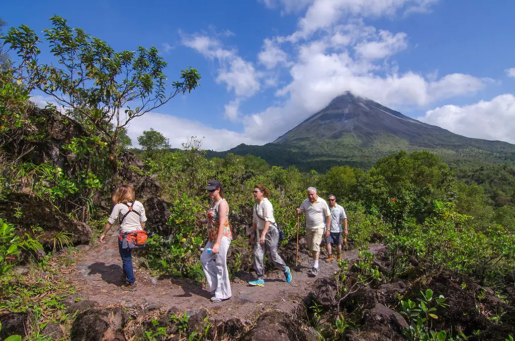Group on a guided hike with the clear cone of Arenal Volcano in the background
